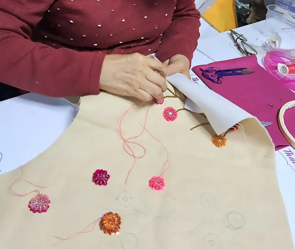 Alumna bordando florecitas en hilo sobre tela clara en clase