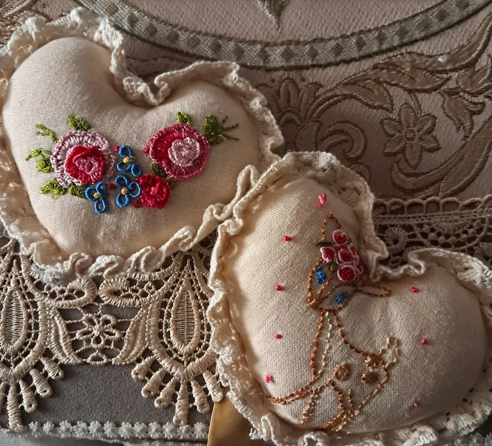 Dos cojines de corazón con rosas de cinta y bordado en hilo, sobre encaje