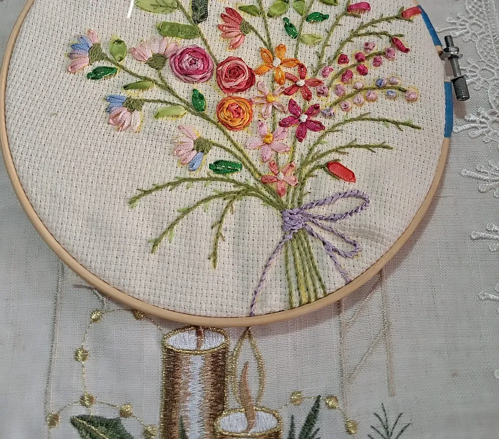 Ramo de flores bordado en hilos de colores con lazo lila, en un bastidor